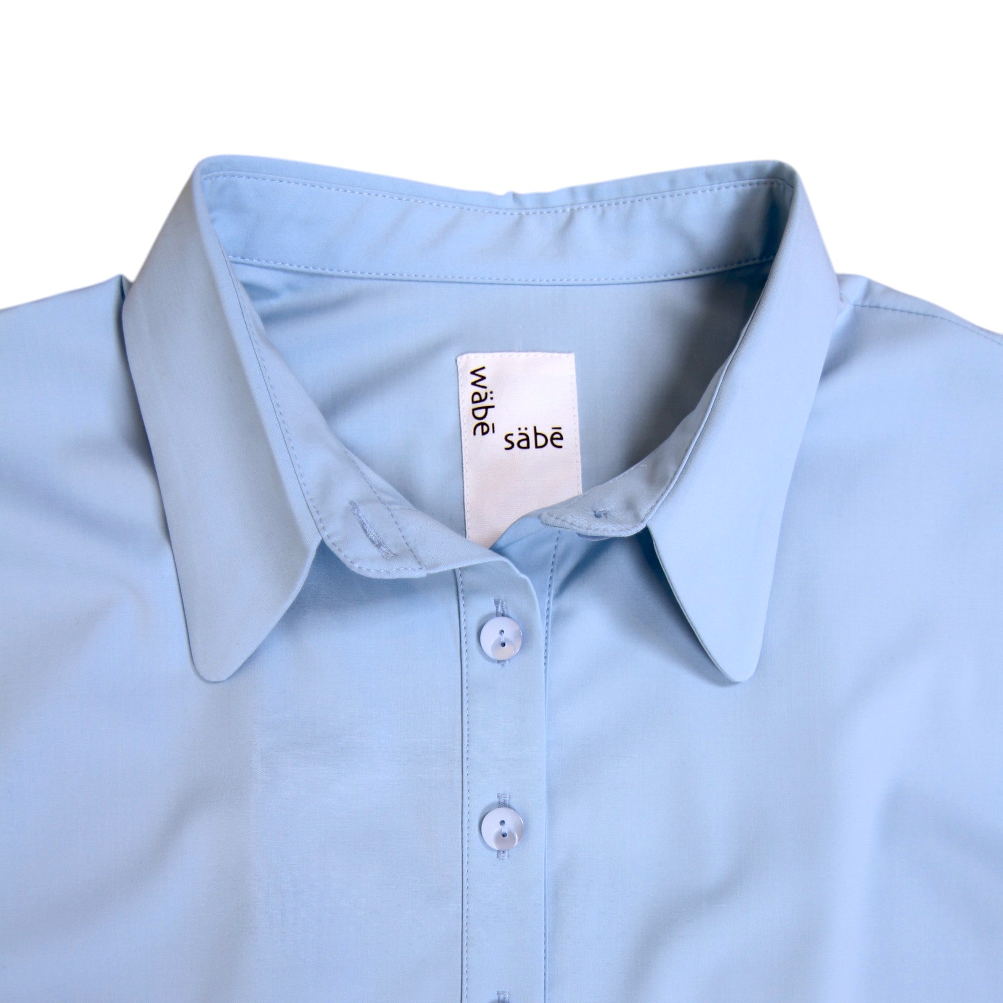 Light blue shirt with a visible brand tag on a white background